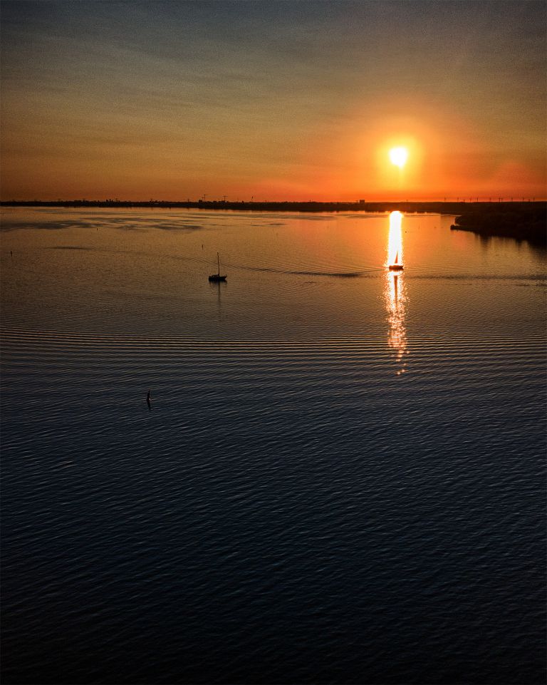 Sailing boats on lake Gooimeer during sunset