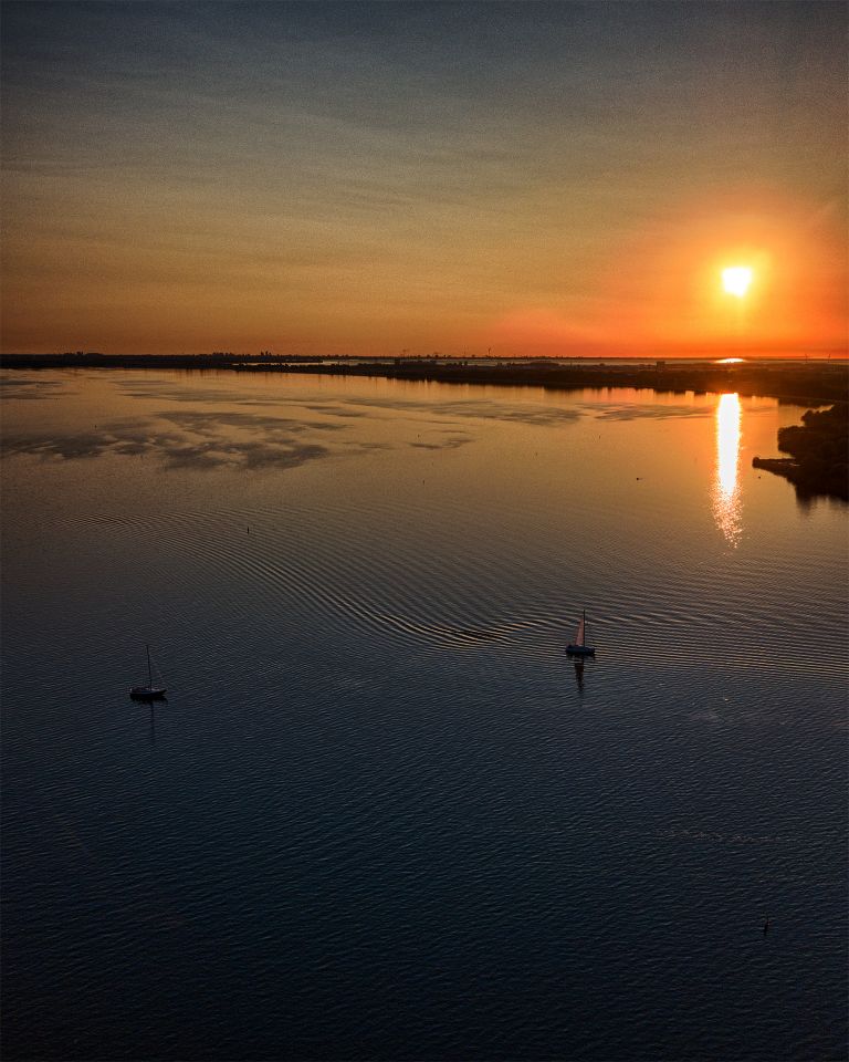 Sailing boats on lake Gooimeer during sunset