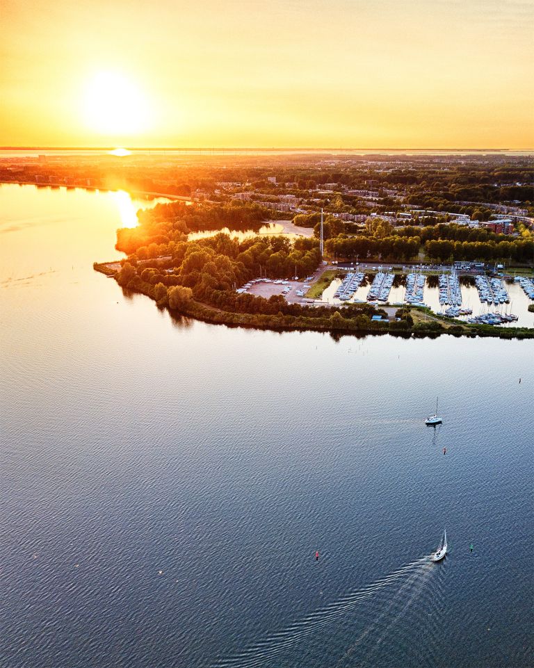 Sailing boats on lake Gooimeer during sunset