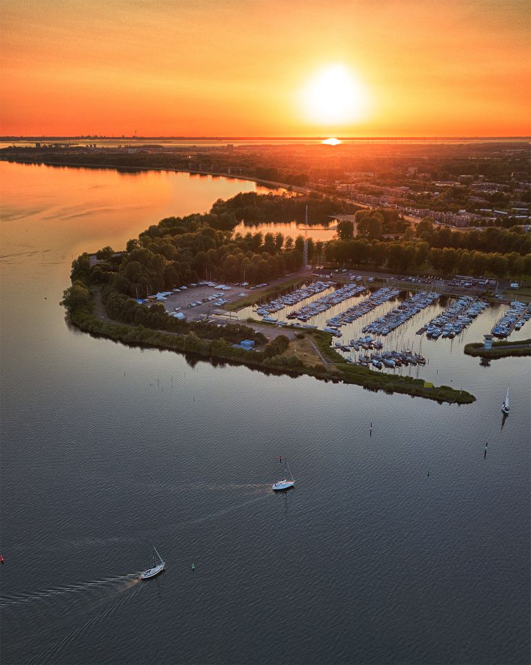 Sailing boats on lake Gooimeer during sunset