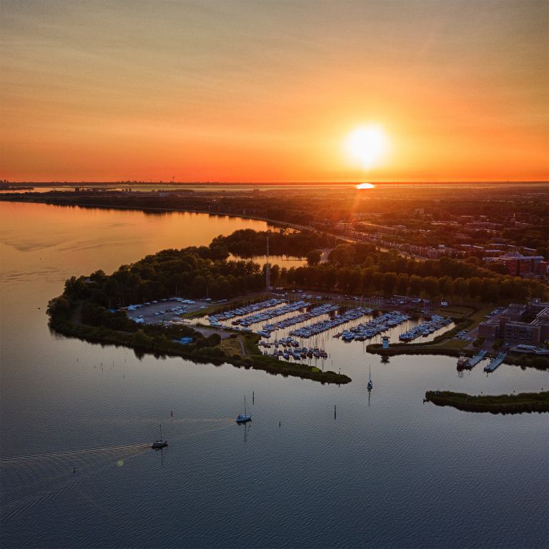 Sailing boats on lake Gooimeer during sunset