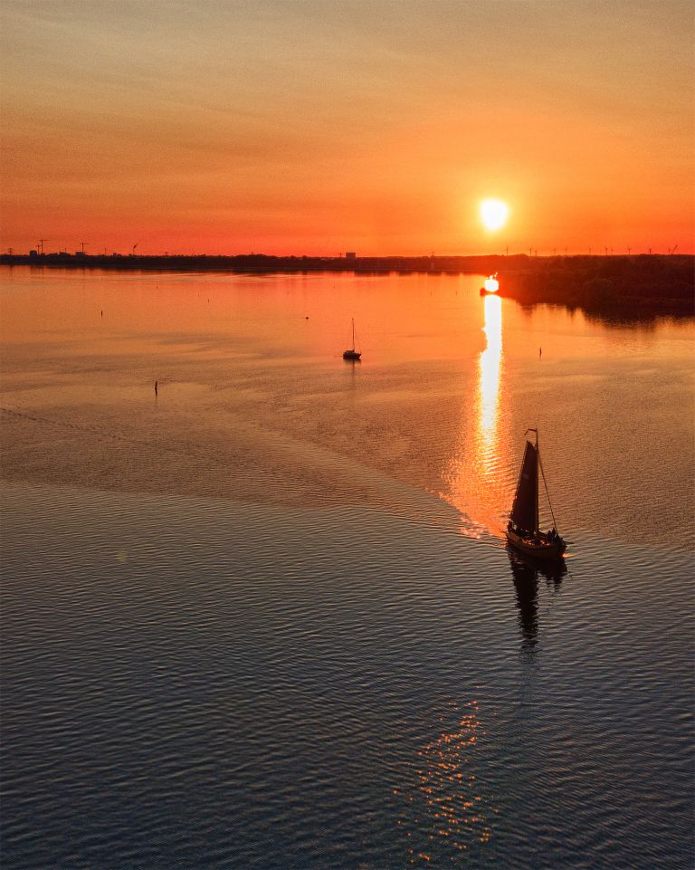 Sailing boats on lake Gooimeer during sunset