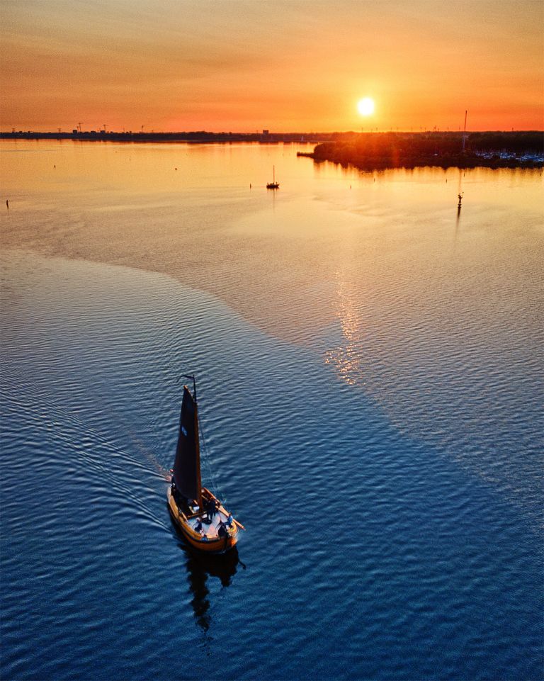 Sailing boats on lake Gooimeer during sunset