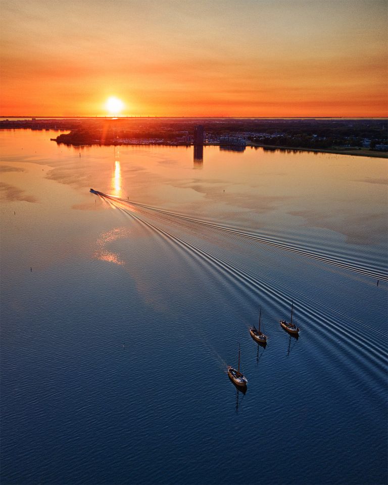 Sailing boats on lake Gooimeer during sunset