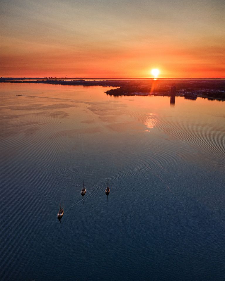 Sailing boats on lake Gooimeer during sunset