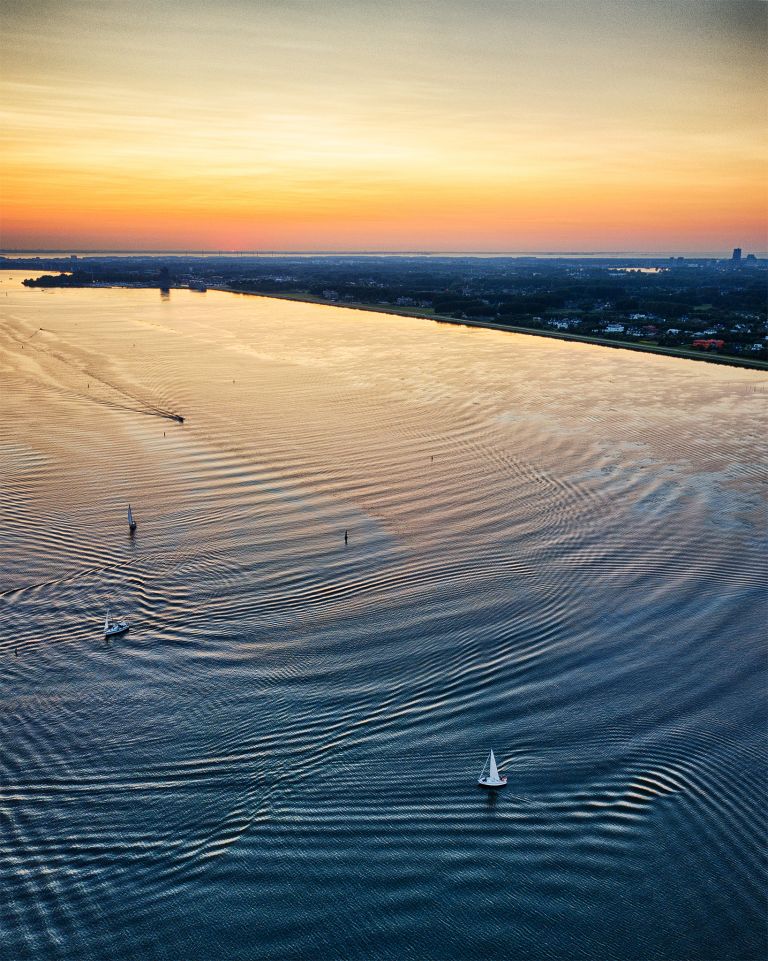 Boats sailing on lake Gooimeer during sunset